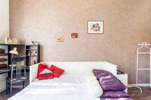 a bedroom with a white bed with red pillows at Indipendent Studio Apartment near metro - Monolocale indipendente vicinissimo metro in Collegno