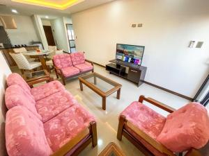 ein Wohnzimmer mit rosa Möbeln und einem Flachbildfernseher in der Unterkunft Perfecto Apartamento Vacacional in Santa Cruz de la Sierra