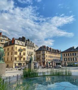 a group of buildings and a fountain in a city at Sweet Home - Cocon élégant climatisé, piscine été, balcon & parking privé in Chambéry