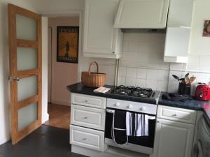 a kitchen with white cabinets and a stove top oven at The Tudors Three Bedroom Apartment in St. Albans