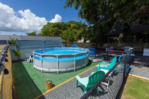 a pool in a yard with green lawn chairs at Casa Lula Beach Retreat - Fenced backyard in Arecibo
