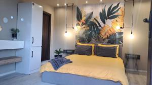 a bedroom with a yellow bed with a painting on the wall at Къща за гости Рилски чардак in Sapareva Banya