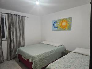 ein Schlafzimmer mit zwei Betten und einem Gemälde an der Wand in der Unterkunft Casa de Praia Planeta Guarajuba in Guarajuba + 45 Fotos