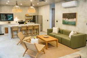 a living room with a green couch and a kitchen at Manuel Antonio Tree House VIllas in Quepos