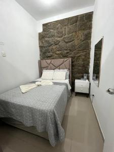 a bedroom with a bed and a stone wall at Albano apartamento 3 en tu refugio Chosica in Chosica