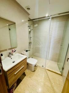 a bathroom with a shower and a toilet and a sink at Appartement Mer & Soleil à EL Mansoria in Pont Blondin