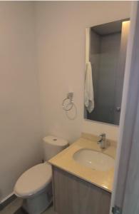 Un baño con inodoro, lavabo y espejo. en Modern suite steps from the sea, en Santa Marta