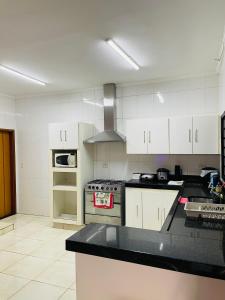 a kitchen with white cabinets and a stove top oven at Casa Coqueiros in Barretos +26 photos