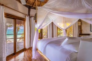 a bedroom with a white bed with a window at Encantada Tulum in Tulum