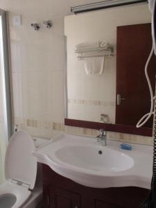 ein Badezimmer mit einem Waschbecken, einem WC und einem Spiegel in der Unterkunft Sabean International Hotel in Aksum
