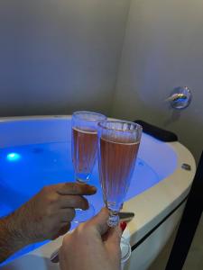 a person holding two glasses in front of a tub at Eco Tiny Latitude 28 in Urubici +28 photos