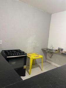cocina con fogones y taburete amarillo en Chácara recanto do girassol, en Aquiraz