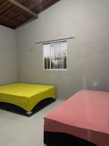 Dos camas en una habitación con ventana. en Chácara recanto do girassol, en Aquiraz