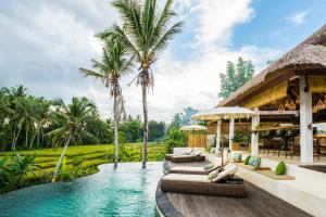 a resort with a swimming pool and palm trees at Calma Ubud Suite & Villas in Ubud