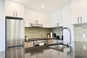 a kitchen with white cabinets and a stainless steel refrigerator at The 708 - For 4 - Free Parking - BBQ in Quebec City