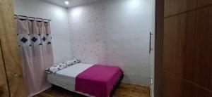 a small bedroom with a bed with a purple blanket at Casa Rústica in Manta