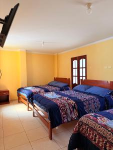 three beds in a room with yellow walls at Hostal La Alborada in Cajamarca