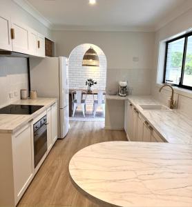 Una cocina con electrodomésticos blancos y una mesa en ella. en Coastal Holiday Home, en Vincentia