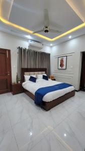 a large bedroom with a large bed with blue sheets at Qayaam Lodges in Islamabad