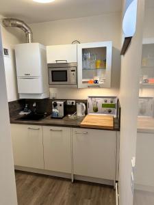 a kitchen with white cabinets and a microwave at Modern, Gemütlich, Strandnah in Cuxhaven
