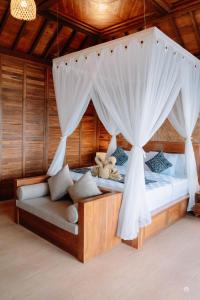 Un dormitorio con una cama con dosel con cortinas y un sofá. en Uma Sunset Villa, en Ubud