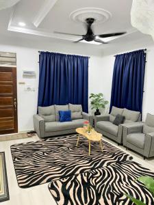 a living room with couches and a table on a zebra rug at Habib Homestay in Kuala Terengganu