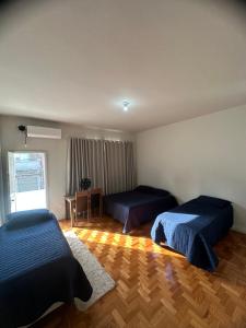 a bedroom with two beds and a table and a window at Quarto Aconchegante in Belo Horizonte
