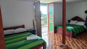 a room with two beds and a balcony with a door at Finca Balcones de Abba in Salento