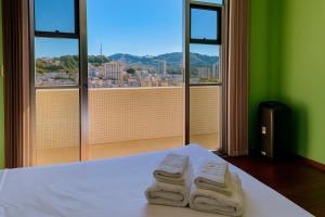 a room with two towels on a bed with a window at Vista Prime Centro - Vista linda. Faça tudo a pé! in São Lourenço