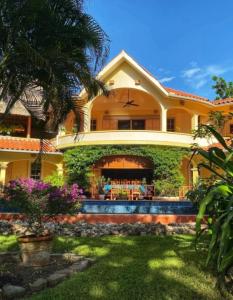 a large yellow house with a palm tree in the yard at Birders' Paradise With Private Pool & Epic Views in Santa Elena