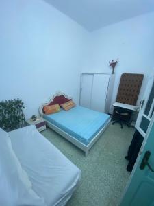 a room with two beds and a chair at Bouchama's Arabesque house in Mahdia
