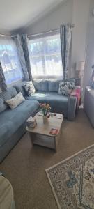 ein Wohnzimmer mit einem blauen Sofa und einem Tisch in der Unterkunft Maise's in Camber