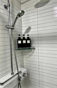 - une douche avec 3 bouteilles sur une étagère dans la salle de bains dans l'établissement Nangman Yeosu, à Yeosu