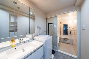 un bagno bianco con lavandino e specchio di LABEL 01 Dotonbori Aparthotel ad Osaka Altre 39 foto