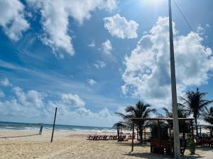 a beach with chairs and palm trees and the ocean at Jfhouse beach in Cascavel