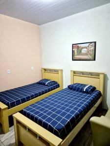 two beds in a room with blue sheets at Casa Miríades in Hortolândia