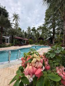una piscina di un resort con fiori rosa in primo piano di Agarwood Garden Resort Phu Quoc a Phu Quoc