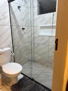 a bathroom with a toilet and a glass shower at Suíte Céu in Congonhas
