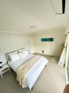 a bedroom with a large white bed in it at Kohi Beach Hideaway in Auckland