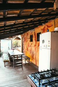 a kitchen with a table and a white refrigerator at Hostel Pantera do Rosa in Praia do Rosa