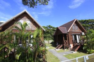 a wooden house with trees in front of it at Tokashiki Guest House in Tokashiki