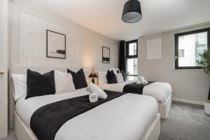 a bedroom with two beds with white and black pillows at Luxury Liverpool City Centre Apartment with Balcony, Sleeps 8, Near Liverpool ONE and Royal Albert Docks in Liverpool