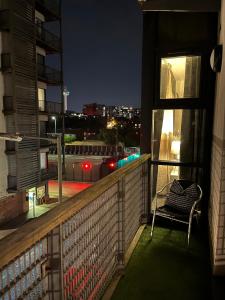a balcony with a chair and a view of a city at night at Luxury Liverpool City Centre Apartment with Balcony, Sleeps 8, Near Liverpool ONE and Royal Albert Docks in Liverpool