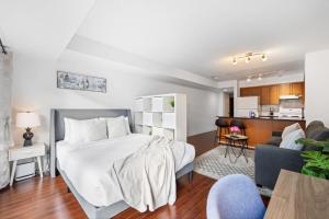 a bedroom with a large white bed and a kitchen at Cozy Urban Retreat Walk to Yonge-Dundas Square in Toronto