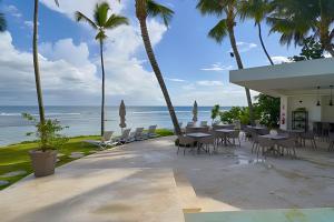 Un restaurante con mesas y sillas y el océano. en Caribbean Ocean View, 2BDRM Beachfront Apartment, en Juan Dolio