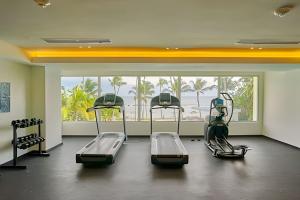 un gimnasio con 3 cintas de correr y una gran ventana en Caribbean Ocean View, 2BDRM Beachfront Apartment, en Juan Dolio