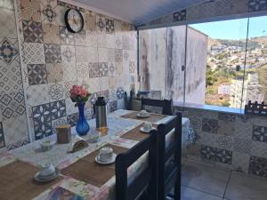 a dining room with a table and a clock on the wall at Hostel Mi Casa Su Casa 1 in Poços de Caldas