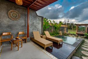un patio con 2 sillas, una mesa y una piscina en Shankara Villa Ubud by Dhananjaya Hospitality, en Tampaksiring