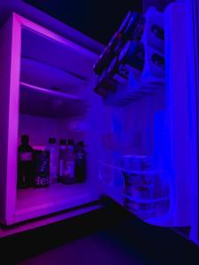 a dark room with a refrigerator with purple lights at La Villa Motel in Mauá +12 photos