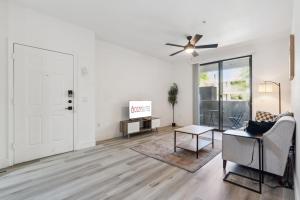 ein Wohnzimmer mit einem Deckenventilator, einem Sofa und einem Tisch in der Unterkunft CozySuites in Glendale Westgate with pool #07 in Glendale